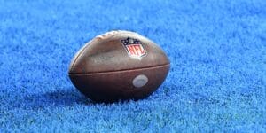 An NFL football laid on the field with a blue background